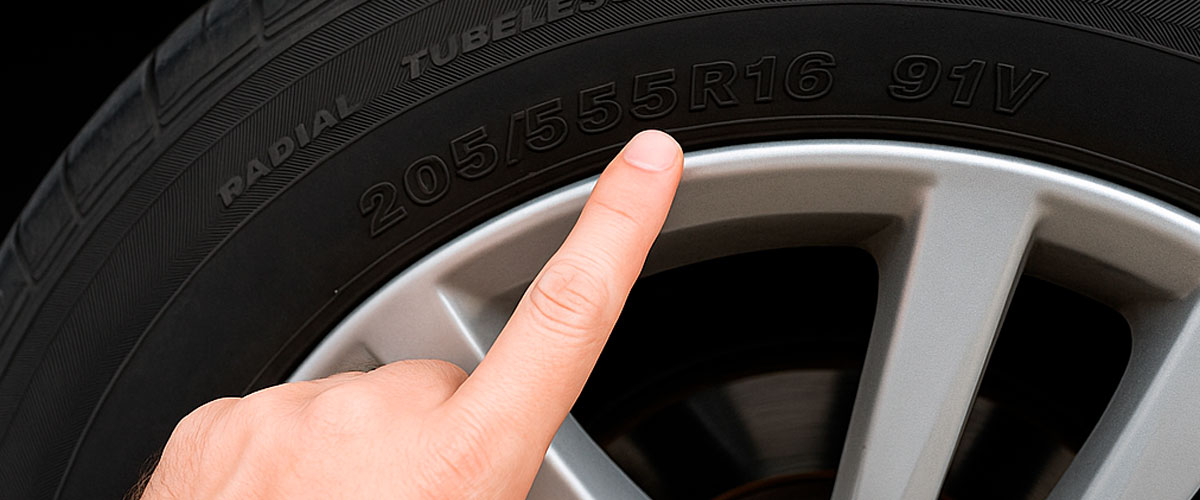 Hombre señala código 205/55R16 91V en llanta para identificar sus especificaciones técnicas